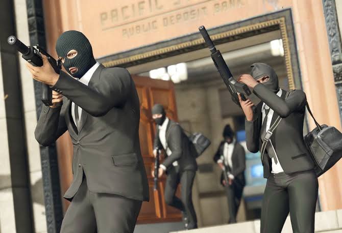 A crew in black suits and masks, carrying weapons, outside a bank